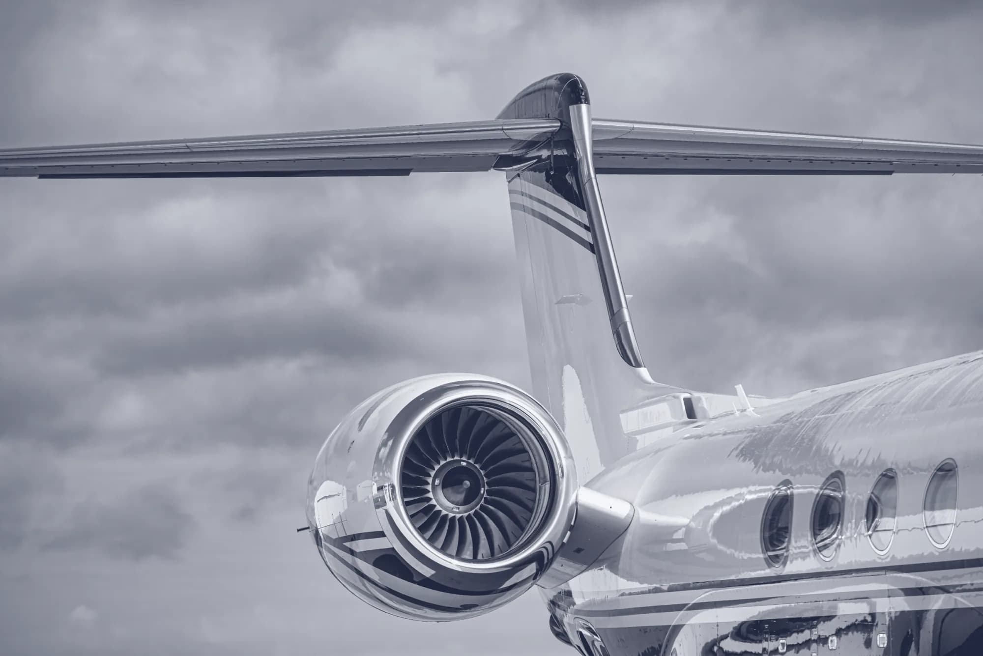 Business jet tail and engine against a cloud sky