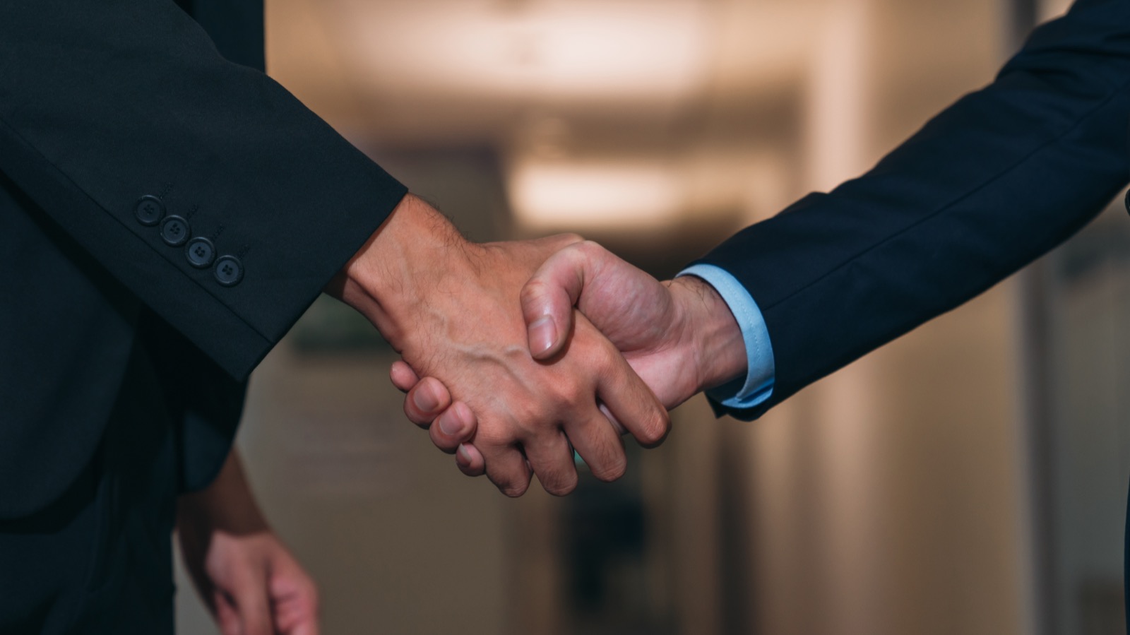 Close-up of two business people shaking hands after resolving a dispute.