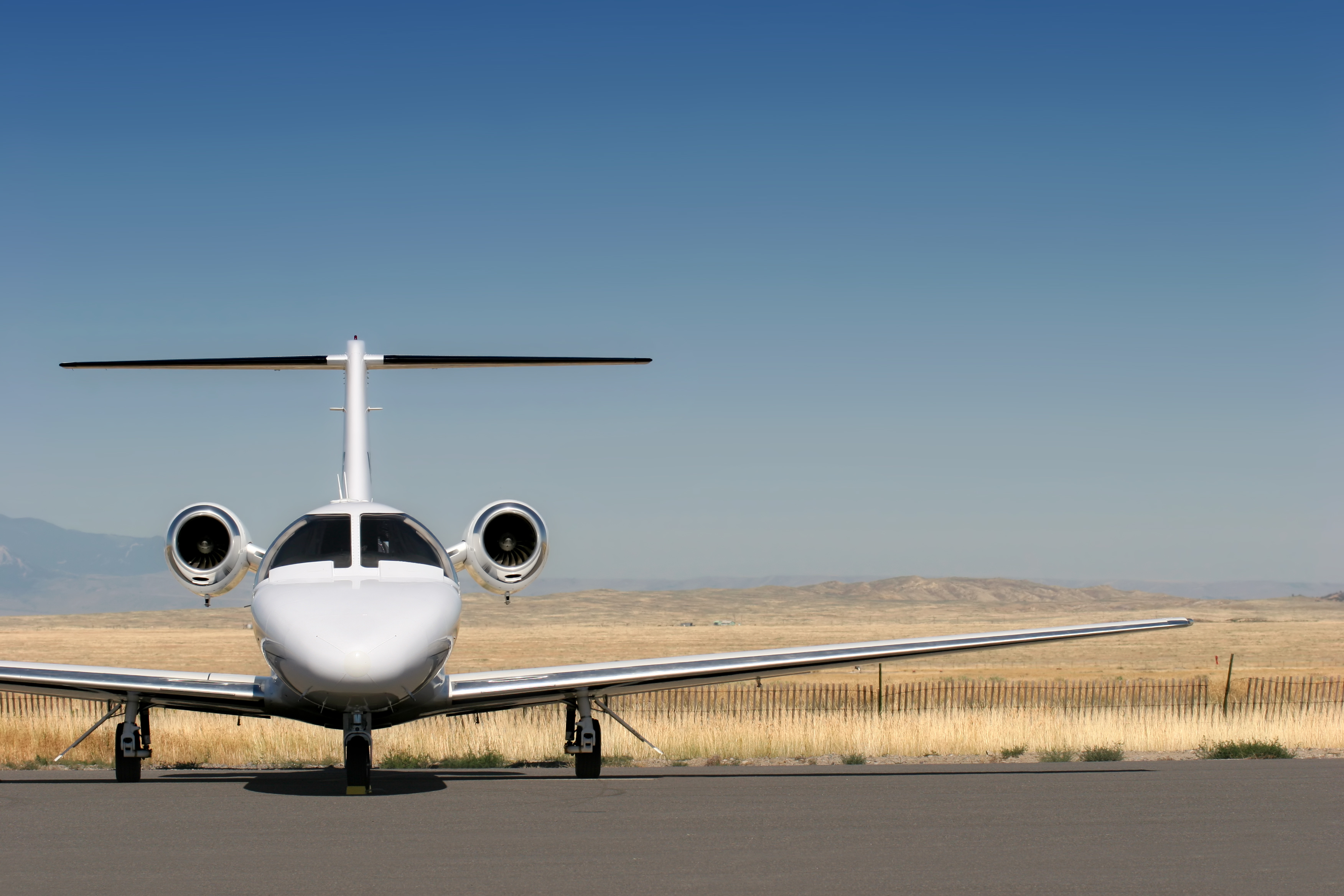 Private business jet parked on the ramp outside a hangar.